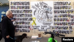 Banorë të Tel Avivit kalojnë pranë një vizatimi që bën thirrje për lirimin e të gjitha pengjeve të rrëmbyera nga Hamasi, që po mbahen në Gazë, më 17 shkurt, 2025/Reuters 
