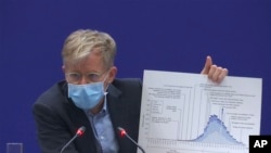 Bruce Aylward, an assistant director-general of the World Health Organization speaks with a chart during a press conference in Beijing on Monday, Feb. 24, 2020. 