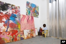Ace-Liam Nana Sam Ankrah, who will turn two in July, paints amidst his own art work at his mother's art gallery in Accra, Ghana, Monday, May 27, 2024. (AP Photo/Misper Apawu)