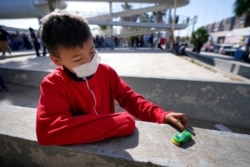 Dany Vargas Rodriguez, 10, of Honduras, plays with a toy car near the McAllen-Hidalgo International Bridge entry point into the U.S. after he and his family were caught trying to sneak into the U.S. and deported, March 18, 2021, in Reynosa, Mexico.