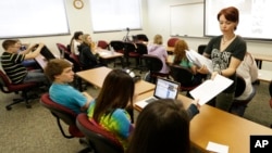 FILE - Adjunct English professor for J. Sargent Reynolds Community College, J. Gabriel Scala, collects papers from her students at her class at the school in Richmond, Va., Wednesday April , 24, 2013. (AP Photo/Steve Helber)