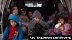 Migrants from Central America take refuge from the rain in the back of a U.S. Border Patrol vehicle as they wait to be transported after crossing the Rio Grande river into the United States from Mexico on a raft in Penitas, Texas, U.S., March 14, 2021. (REUTERS/Adrees Latif)