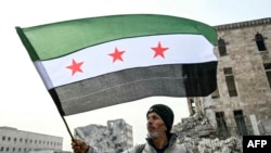 2024 年 12 月 11 日，一名男子在敘利亞北部阿勒頗城堡揮舞敘利亞反對派旗幟。(法新社照片)