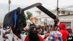 Un manifestante enmascarado empuña un machete durante una protesta contra el primer ministro haitiano, Ariel Henry, en Puerto Príncipe, Haití, el lunes 5 de febrero de 2024.
