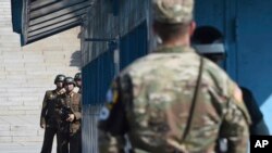 FILE - North Korean soldiers, left, look at the South side while U.S. Defense Secretary Jim Mattis and South Korean Defense Minister Song Young-moo visit the truce village of Panmunjom in the Demilitarized Zone (DMZ) on Oct. 27, 2017. (Jung Yeon-je/Pool Photo via AP)