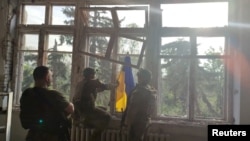 Soldados colocan una bandera ucraniana en un edificio, durante una operación que pretende liberar la primera aldea en medio de una contraofensiva, en un lugar indicado como Blahodatne, región de Donetsk, Ucrania, captura de pantalla de un video publicado el 11 de junio de 2023