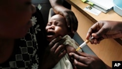 FILE - A mother holds her baby receiving a new malaria vaccine as part of a trial at the Walter Reed Project Research Center in Kombewa in Western Kenya. 
