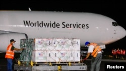 Les travailleurs des transporteurs aériens transportent des doses de vaccin Moderna données par le gouvernement américain dans le cadre du programme COVAX contre la maladie à coronavirus (COVID-19) à l'aéroport international Oscar Arnulfo Romero, El Salvador, le 5 juillet 2021.