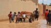 Des enfants transportent de la latérite sur un chariot pour construire des barrages afin d'arrêter les eaux du fleuve Niger à Niamey le 3 septembre 2019.
