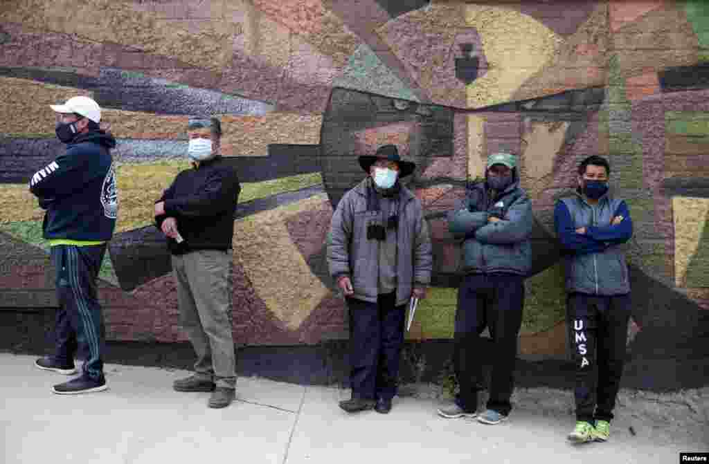 Un grupo de votantes hacen fila, mientras usan máscaras protectoras, y esperan en un colegio electoral para poder sufragar durante las elecciones presidenciales en La Paz, Bolivia.