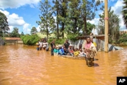 A family uses a boat after fleeing floodwaters that wreaked havoc in the Githurai area of Nairobi, Kenya, April 24, 2024.