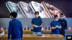 Employees wear face masks as they stand in a reopened Apple Store in Beijing, Friday, Feb. 14, 2020. China on Friday reported another sharp rise in the number of people infected with a new virus, as the death toll neared 1,400. Apple had closed all…