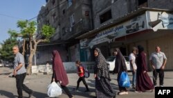 Palestinos llevando sus pertenencias huyen a áreas más seguras en la Ciudad de Gaza después de ataques aéreos isaelíes el 13 de octubre de 2023.