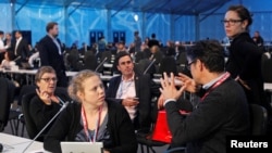 Un grupo de delegados conversan durante la plenaria de la COP28, en Lima, el 12 de diciembre de 2023.