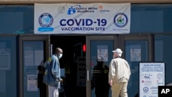 Deux hommes arrivent à une clinique de vaccination COVID-19 au centre commercial Auburn à Auburn, Maine, le 12 mai 2021.