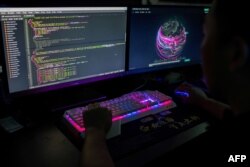 Seorang anggota kelompok peretas Red Hacker Alliance yang menolak menyebutkan nama aslinya, menggunakan situs web yang memantau serangan siber global di komputernya di kantor mereka di Dongguan, Guangdong selatan China. (Foto: AFP)