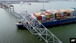 El carguero Dali bajo parte de la estructura colapsada del puente Francis Scott Key en Baltimore, EEUU, el 26 de marzo de 2024. [Foto de la Junta Nacional de Seguridad en el Transporte distribuida por AP].