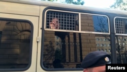 Arhiva - Policajac stoji ispred autobusa sa novinarima uhapšenim tokom mitinga u Moskvi, 7. jula 2019.