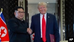 Trump na Kim wapeana mkono baada ya kutia saini taarifa baada ya mkutano wao.