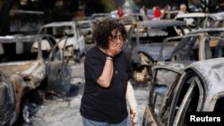 Жінка намагається знайти свою собаку після лісової пожежі в селі Маті, поблизу Афін, Греція. 24 липня 2018 року.
