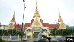 រូបឯកសារ៖ បុរស​ម្នាក់​បើក​ម៉ូតូ​កាត់​មុខ​រដ្ឋ​សភា​ក្នុង​ក្រុង​ភ្នំពេញ កាលពីល្ងាចថ្ងៃទី២ ខែឧសភាឆ្នាំ២០១៨។ (អូន ឆេងប៉រ/វីអូអេ)