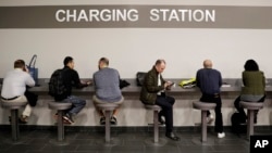 FILE - Show attendees charge their phones at the charging station at CES International Thursday, Jan. 5, 2017, in Las Vegas. (AP Photo/Jae C. Hong)