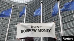 Students display a banner outside the EU Commission headquarters ahead of an European Union summit in Brussels December 8, 2011. European Union leaders will discuss proposals for tighter euro zone integration on December 8 to 9, with the aim of bringing d