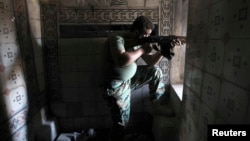 A Free Syrian Army fighter aims his weapon as he takes position inside a house in the city of Aleppo July 11, 2013. 