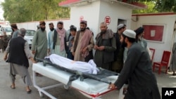 Afghans carry the body of a man who was killed during an attack, in the southern Helmand province, Monday, June 29, 2020. A car bombing and mortar shells fired at a busy market in southern Afghanistan's Helmand province on Monday killed over 20…