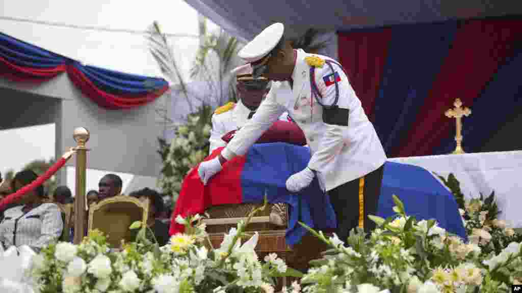 Un policier ajuste le drapeau sur le cercueil contenant les l'ancien président René Préval lors du service à Port-au-Prince, Haïti, le samedi 11 mars 2017.
