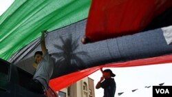 Jamal Goubtan, quien es residente en Libia, ayuda a desplegar una gigantesca bandera en Trípoli.