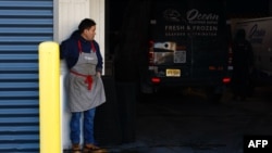 แรงงานยืนที่ด้านหน้าลานจอดรถของร้านค้า ที่เจ้าหน้าที่ตรวจคนเข้าเมืองและศุลกากรเข้าบุกจับแรงงาน ในเมืองนวร์ก รัฐนิวเจอร์ซีย์ วันที่ 24 มกราคม 2025 (ที่มา: AFP)