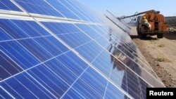 2018年10月22日工人在中国新疆维吾尔自治区哈密的光伏产业园操作机器清洁太阳能电池板