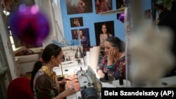 Roma sisters Helena, left, and Erika Varga work on a production in their fashion studio, Romani Design, in Budapest, Hungary, December 12, 2021. (AP Photo/Bela Szandelszky)