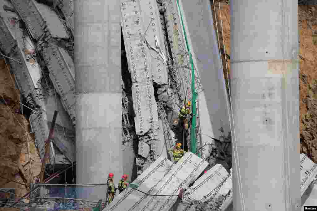 Rescue workers participate in a salvage operation at a collapsed highway construction site in Cheonan, South Korea.