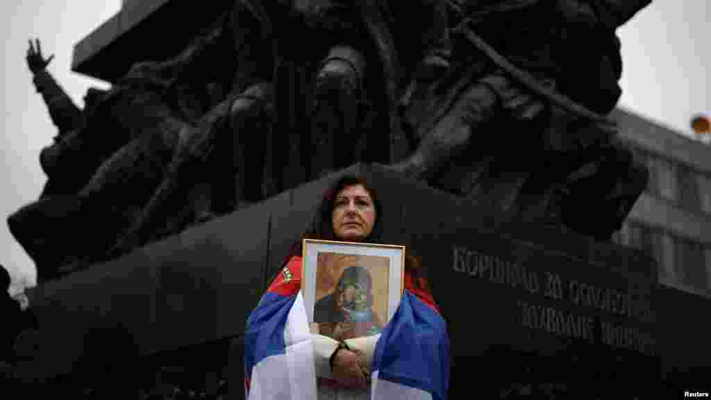 Žena drži ikonu Bogorodice ispred spomenika borcima za oslobođenje na protestu "Studentski edikt"u Nišu (REUTERS/Stojan Nenov)
