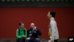 一對外國遊客參觀北京胡同時在雍和宮附近的長椅上休息。 (2024年10月30日)