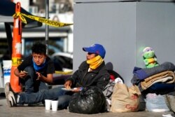 Migrants who were caught trying to sneak into the United States and were deported eat near the McAllen-Hidalgo International Bridge point of entry into the U.S., March 18, 2021, in Reynosa, Mexico.