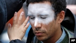 In this Oct. 31, 2018, file photo, a man, who declined to be identified, has his face painted to represent efforts to defeat facial recognition during a protest at Amazon headquarters over the company's facial recognition system, "Rekognition," in Seattle