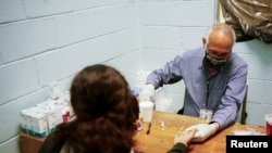 Un doctor asiste a una inmigrante centroamericana que busca refugio en México y fue alojada en un asilo temporal en Ciudad Juárez en abril de 2021.