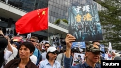 People hold a China national flag and signs as they participate in a pro-government rally to show their support for the police and government at the Legislative Council (LegCo) building in Hong Kong, China, November 16, 2019. REUTERS/Athit…
