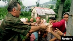 ARHIVA - Komandant vojske bosanski Srba Ratko Mladić, pruža hranu bosanskim muslimanima, izbeglicama iz Srebrenice 12. jula 1995. (Foto: Reuters)
