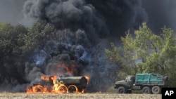 Vehículos militares sin insignias se incendian en una carretera en el este de Ucrania, cerca de Mariupol.