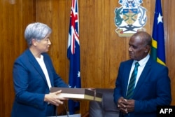 澳大利亚外交贸易部发布照片显示，澳大利亚外长黄英贤向到访的所罗门群岛总理杰里迈亚·马内莱（Jeremiah Manele）赠送礼物。（2024年6月5日）