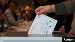 2024年10月8日立陶宛維爾紐斯一名選民在立陶宛大選提前投票期間將選票投入選票箱。