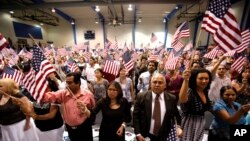 FILE - People hold flags as they are sworn in as U.S. citizens during a naturalization ceremony in Phoenix, Arizona.