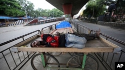 Homeless men sleep on a handcart parked on a road divider in a containment zone during lockdown in Bengaluru, India, Sunday, July 5, 2020. India's coronavirus caseload is fourth in the world behind the U.S., Brazil and Russia. (AP Photo/Aijaz Rahi)