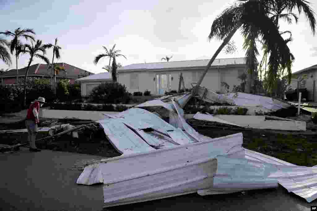 A roof is strewn across a home's lawn as Rick Freedman checks his neighbor's damage from Hurricane Irma in Marco Island, Florida, Sept. 11, 2017.