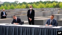 Američki državni sekretar Entoni Blinken (L) i nemački ministar inostranih poslova Hajko Mas potpisuju sporazum o pokretanju Dijaloga SAD i Nemačke o holokaustu, pored spomenika žrtvama holokausta u Berlinu (Foto: AP/Markus Schreiber)