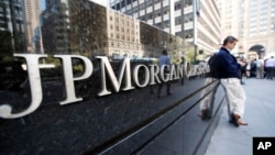 FILE - A man pauses outside one of two JPMorgan Chase & Co. buildings on Park Avenue in midtown Manhattan in New York.